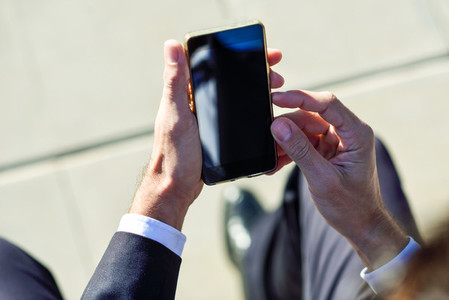 Businessman using his smartphone in the street