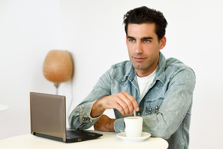 Good looking man wearing denim shirt sitting in a coffee bar