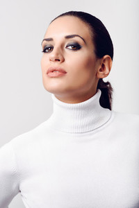 Young brunette woman wearing white poloneck in studio shot