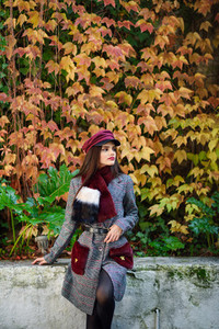Young beautiful girl with very long hair wearing winter coat and cap in autumn leaves background