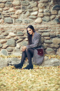 Young girl with very long hair wearing winter coat sitting on the floor full of autumn leaves