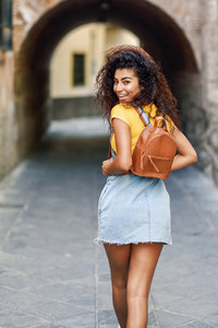 Young black tourist woman with curly hairstyle outdoors