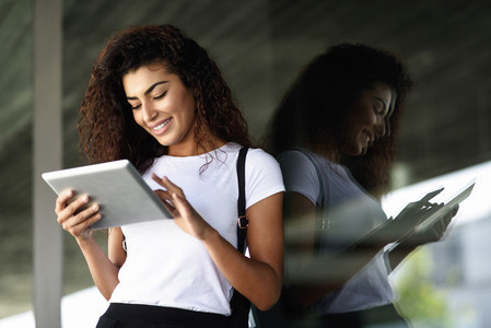 Young Arab woman with looking at her digital tablet outdoors
