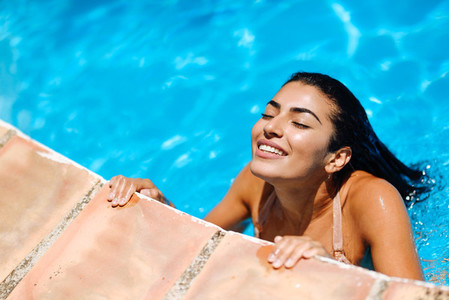 Beautiful Arab woman relaxing in swimming pool