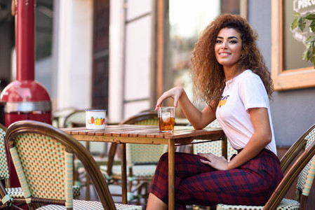 Arab girl in casual clothes drinking a soda in an outdoors bar