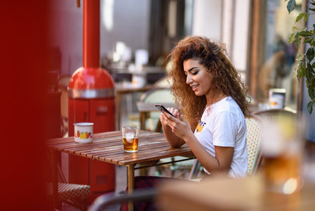 Arab woman in an urban bar at her smartphone