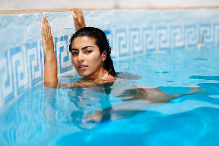 Beautiful Arab woman relaxing in swimming pool