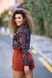 Happy young arabic woman with black curly hairstyle