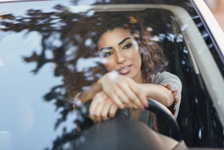 Young arabic woman inside a white car looking through the window
