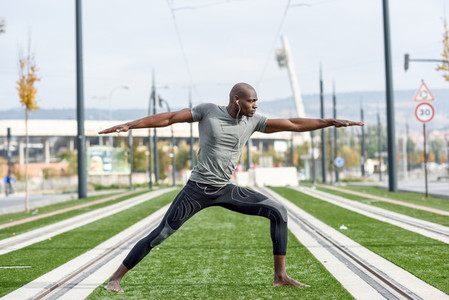 Black man practicing yoga in urban background