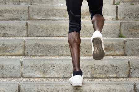Athletic legs of black man running on staircase steps