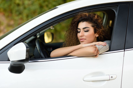 Young arabic woman inside a white car with eyes closed