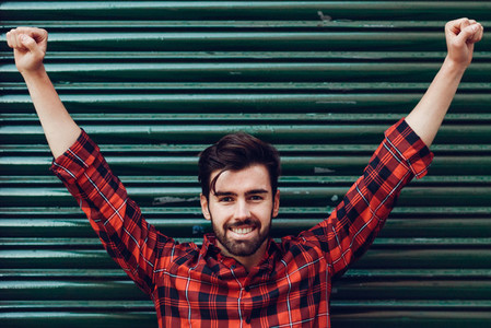 Young smiling man open arms wearing a plaid shirt with a green
