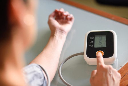 Woman measuring her own blood pressure at home