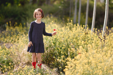 Little girl walking in nature field wearing beautiful dress