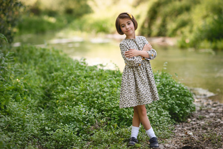 Little girl in nature stream wearing beautiful dress