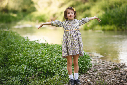 Little girl in nature stream wearing beautiful dress