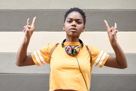 Young black woman making the gesture of the horns with her hands outdoors