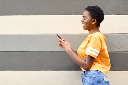 Black girl smiling and using her smart phone outdoors
