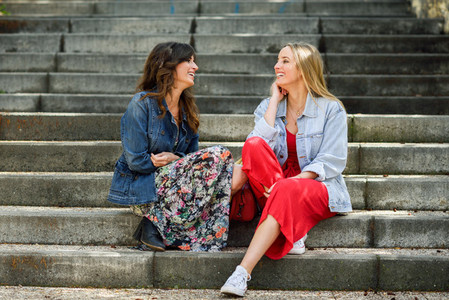 Two young women talking and laughing on urban steps