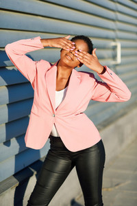 Funny black woman standing on urban wall covering her eyes with her hands