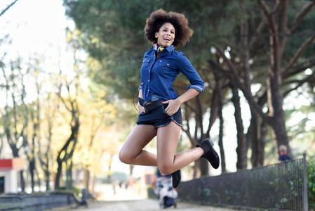 Young black woman with afro hairstyle jumping in urban backgroun