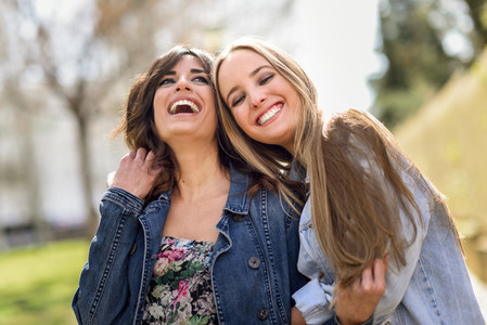 Two happy young women friends hugging in the street
