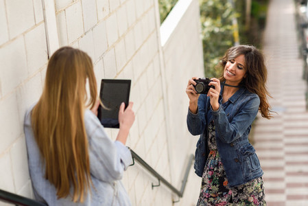 Two young tourist women taking photographs outdoors