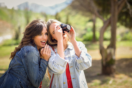 Two young tourist women taking photographs outdoors