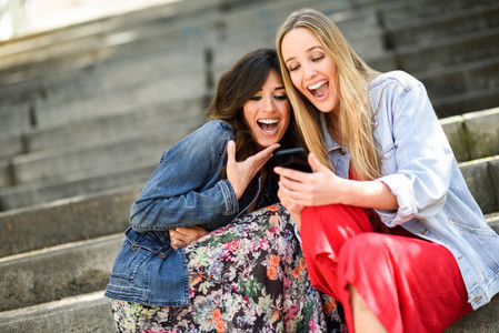 Two girls looking at some funny thing on their smart phone