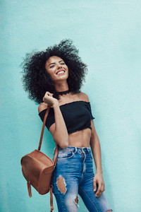 Happy mixed woman with afro hair standing on the street