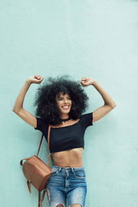 Funny black woman with afro hair raising arms outdoors