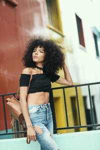 Young mixed woman with afro hair standing on the street
