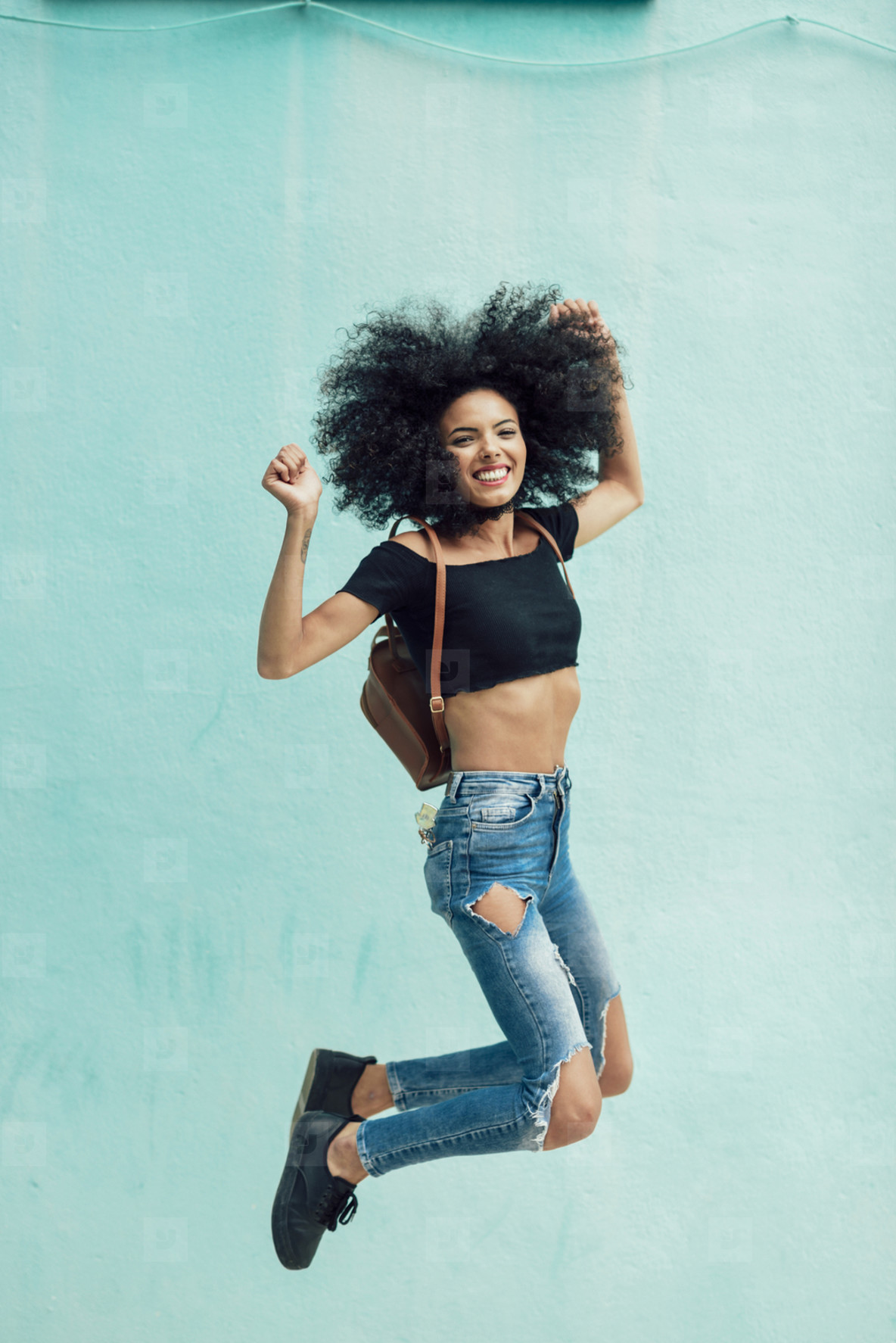 Young mixed woman with afro hair jumping outdoors