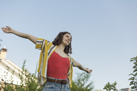 Carefree woman with arms outstretched in back yard