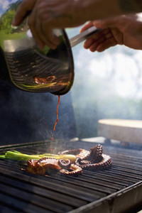 Chef pouring sauce over squid on octopus