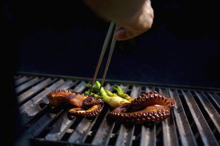 Chef with chopsticks grilling octopus