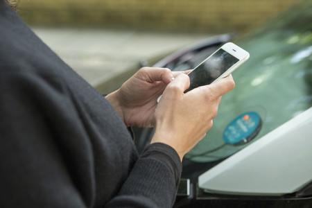 Close up woman using smart phone to access car share