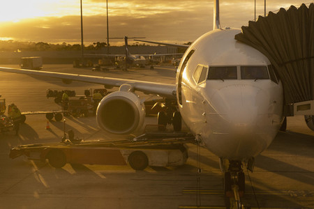 Commercial airplane parked at terminal on tarmac at sunset