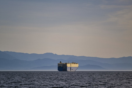 Container ship on sunny  idyllic ocean with Olympic Mountain Range in background