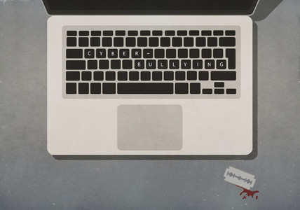 Cyber Bullying text on laptop next to razor blade with blood