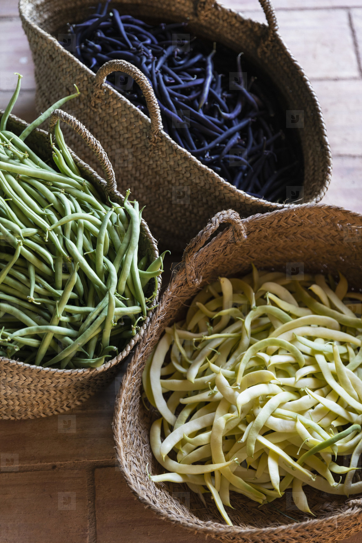 Fresh harvested variety of yellow  green and purple beans in straw baskets