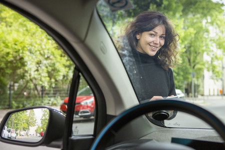 Portrait smiling young woman with smart phone accessing car share