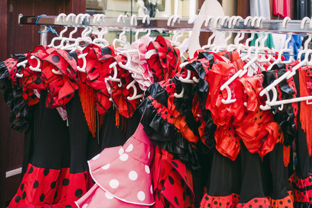 Red and black polka dot costume dresses hanging on clothes rack in shop