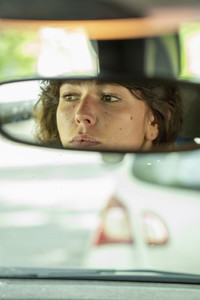 Reflection of woman in rear view mirror driving car