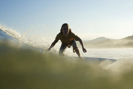 Silhouette boy surfer riding ocean wave