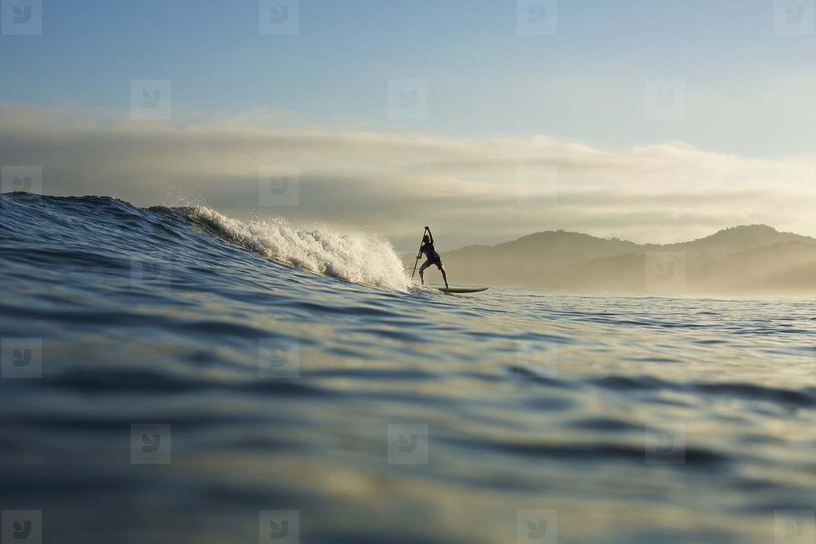 Silhouette paddle boarder riding ocean wave, Sayulita, Nayarit, Mexico