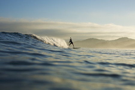Silhouette paddle boarder riding ocean wave Sayulita Nayarit Mexico