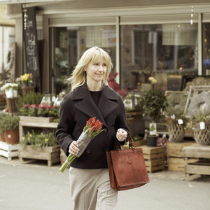 Woman carrying bunch of tulips on urban sidewalk