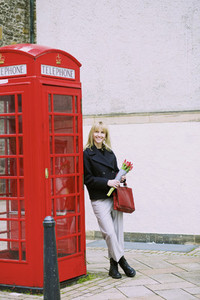 Woman with bunch of tulips leaning against red telephone box